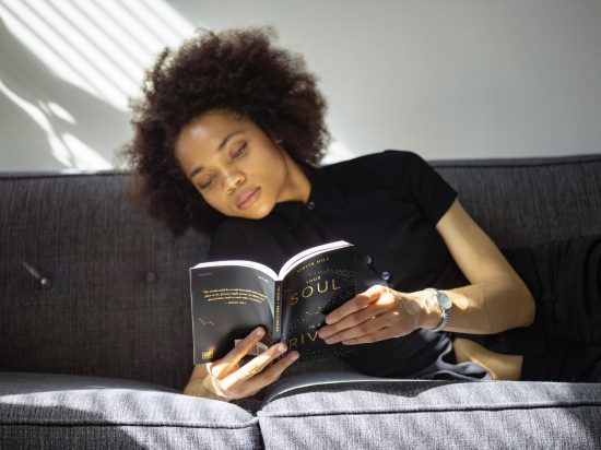 woman reading book on sofa